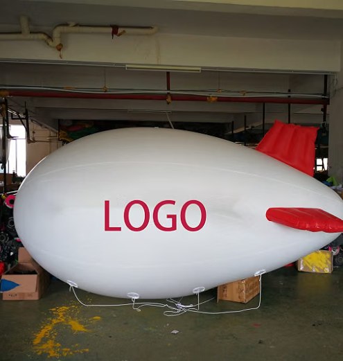 13 ft PVC advertising blimp, about 6.5 ft wide, with inflatable PVC fins, lying on a factory floor