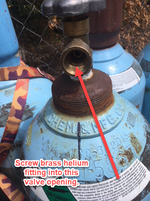 Close-up of a helium cylinder valve showing the threaded brass opening where the fill fitting screws in